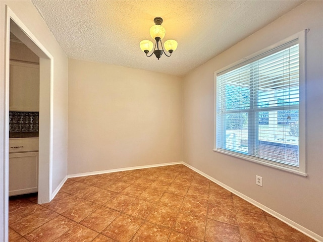 empty room with an inviting chandelier and a textured ceiling