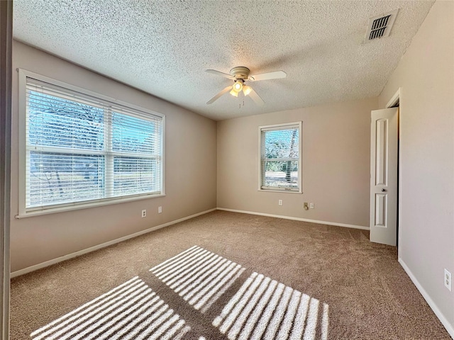 spare room with ceiling fan, light colored carpet, and a healthy amount of sunlight