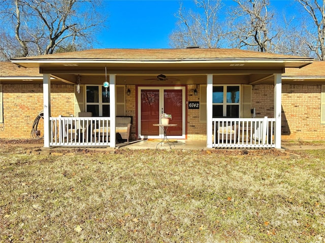 view of exterior entry featuring ceiling fan, a yard, and covered porch