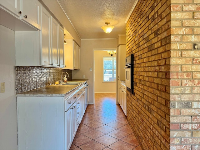 kitchen featuring sink, a textured ceiling, ornamental molding, oven, and white cabinets