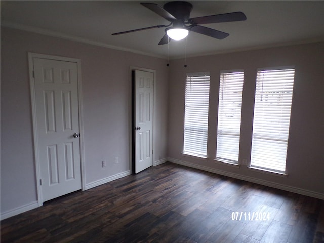 empty room featuring dark wood-type flooring, ornamental molding, and a healthy amount of sunlight