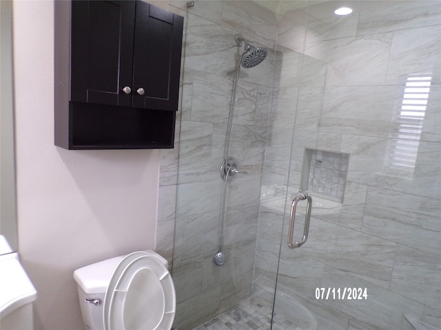 bathroom with a shower with door and toilet