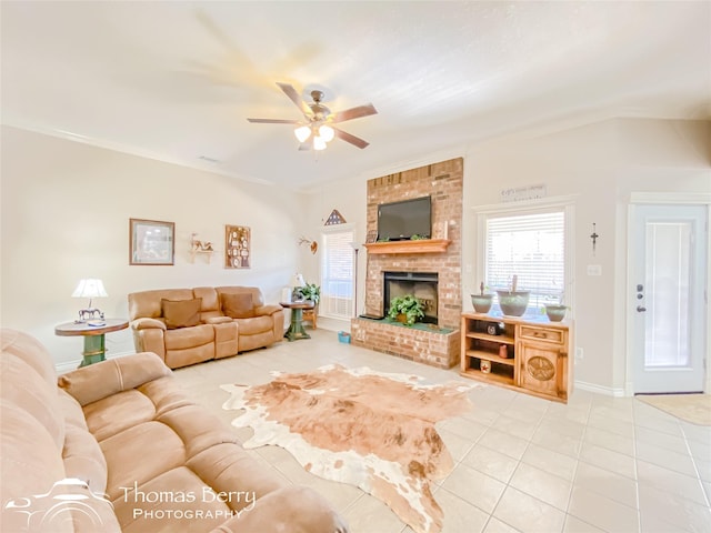 tiled living room featuring ceiling fan, a brick fireplace, and a wealth of natural light