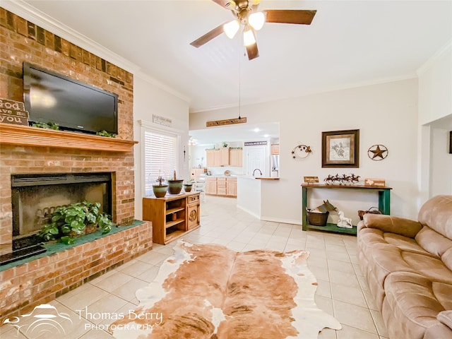 living room with light tile patterned flooring, sink, crown molding, ceiling fan, and a fireplace