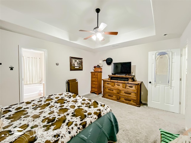 bedroom with a tray ceiling, light colored carpet, and ceiling fan