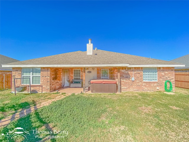 rear view of house featuring a patio area, a hot tub, and a lawn