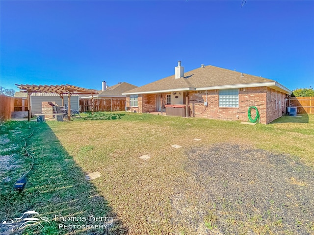 back of property featuring a hot tub, a pergola, and a lawn