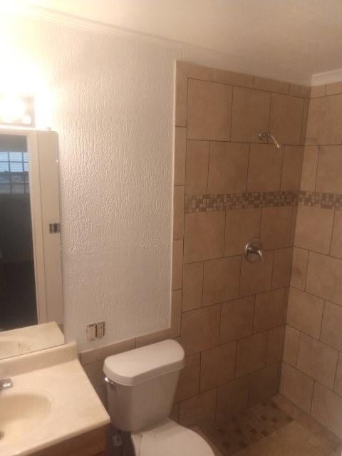 bathroom featuring vanity, toilet, and a tile shower