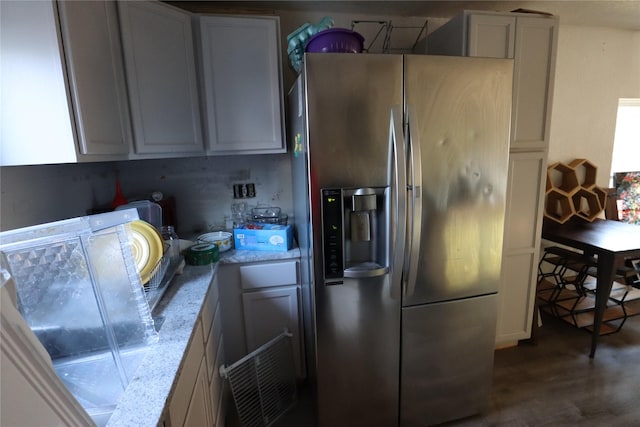 kitchen with dark hardwood / wood-style floors, light stone counters, and stainless steel fridge with ice dispenser