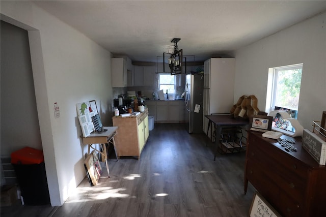 kitchen featuring hanging light fixtures, dark hardwood / wood-style floors, white cabinets, and stainless steel refrigerator