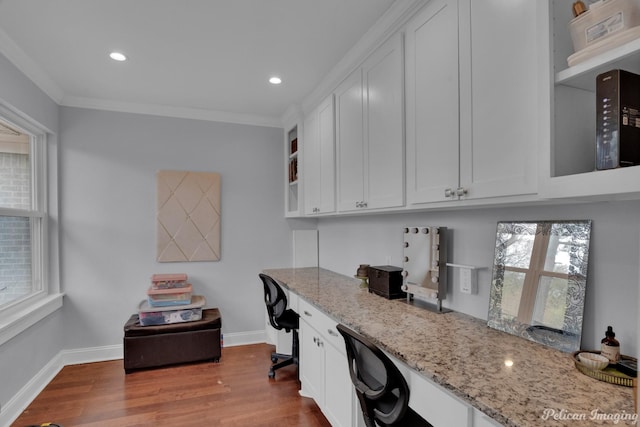 office area featuring ornamental molding, built in desk, and light hardwood / wood-style flooring