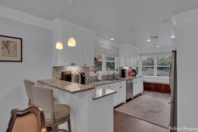 kitchen with sink, white cabinetry, light stone counters, decorative light fixtures, and kitchen peninsula