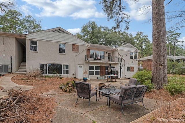 rear view of property featuring a balcony, central AC unit, and a fire pit