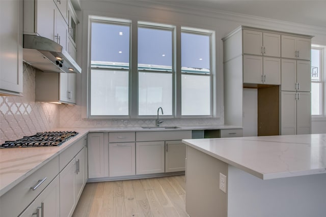 kitchen featuring sink, crown molding, light stone countertops, and stainless steel gas cooktop