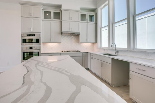 kitchen with stainless steel appliances, sink, and light stone counters