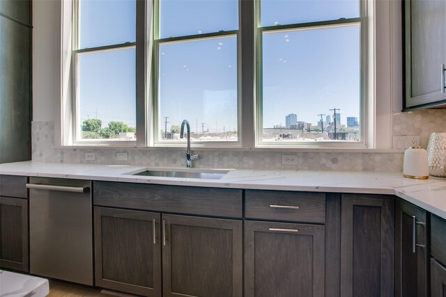 kitchen with tasteful backsplash, dishwasher, sink, light stone countertops, and dark brown cabinets