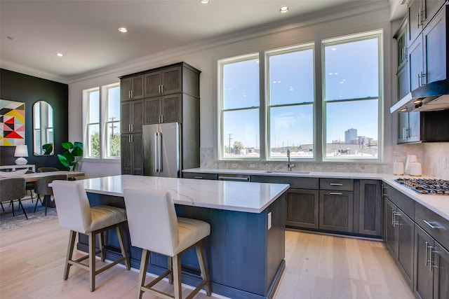 kitchen with a breakfast bar, sink, crown molding, appliances with stainless steel finishes, and a kitchen island