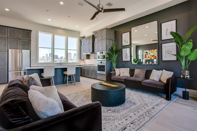 living room featuring ornamental molding, ceiling fan, and light hardwood / wood-style flooring