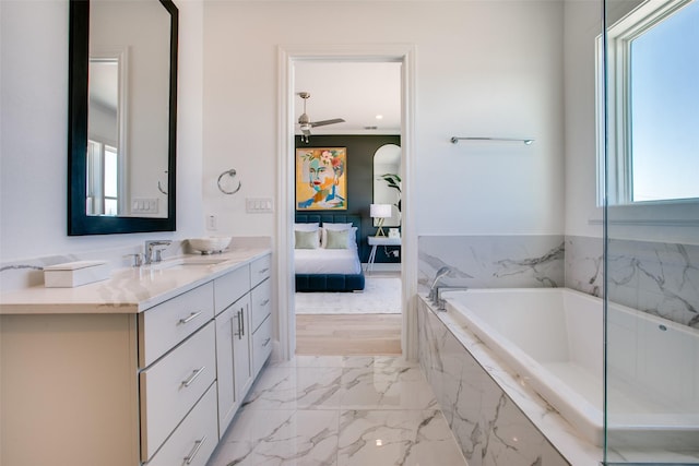 bathroom with vanity, a relaxing tiled tub, and ceiling fan