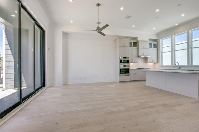 kitchen featuring white cabinetry, tasteful backsplash, ornamental molding, light hardwood / wood-style floors, and black cooktop