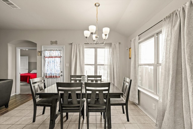 tiled dining space featuring plenty of natural light, a chandelier, and vaulted ceiling