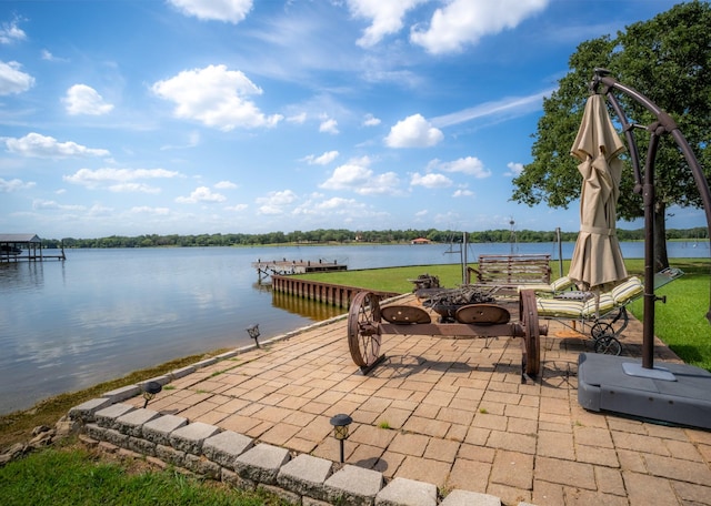 view of patio with a water view, a fire pit, and a boat dock