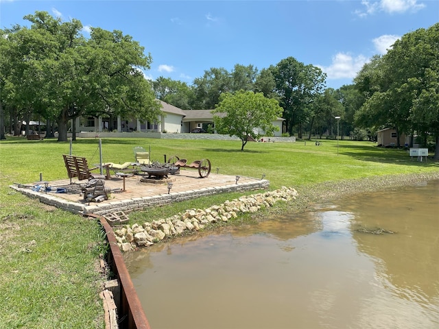 exterior space featuring a water view, an outdoor fire pit, and a yard