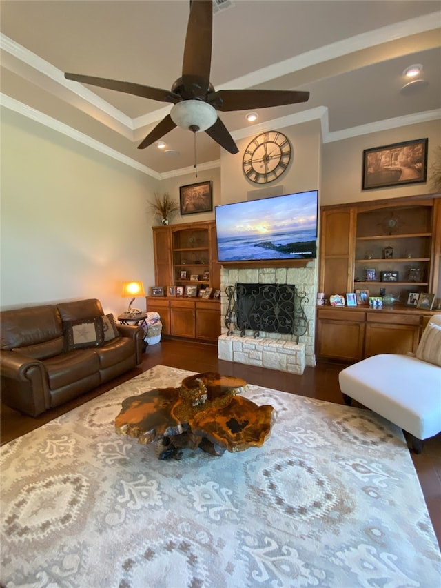 living room with ornamental molding, a stone fireplace, dark hardwood / wood-style floors, and ceiling fan