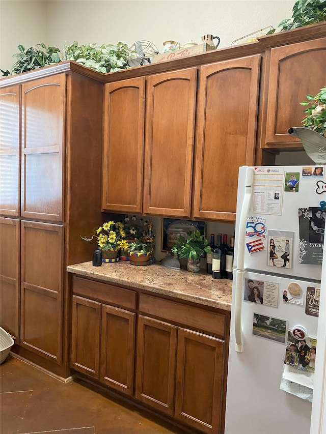 kitchen with light stone countertops and white fridge