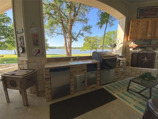 view of patio / terrace featuring a water view, a grill, and exterior kitchen