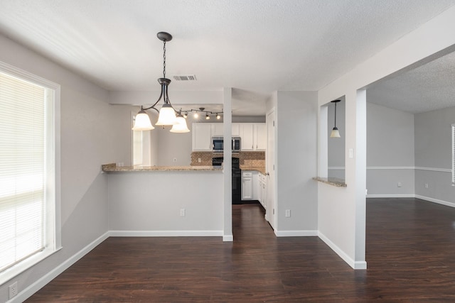 kitchen featuring light stone counters, kitchen peninsula, hanging light fixtures, and white cabinets