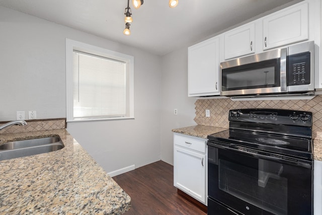 kitchen featuring black electric range, sink, white cabinets, and light stone counters