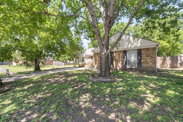 view of front of home with a front yard, brick siding, and fence