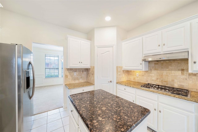 kitchen with tasteful backsplash, dark stone countertops, light tile patterned floors, stainless steel appliances, and white cabinets