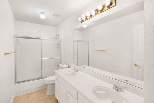 full bathroom featuring vanity, bath / shower combo with glass door, tile patterned floors, and toilet