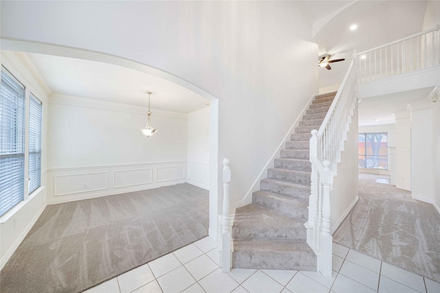 stairway with crown molding, carpet floors, and ceiling fan