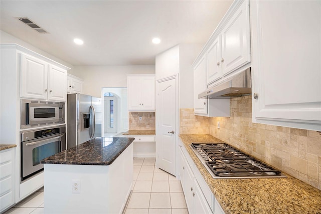 kitchen with stainless steel appliances, a kitchen island, light tile patterned floors, and white cabinets