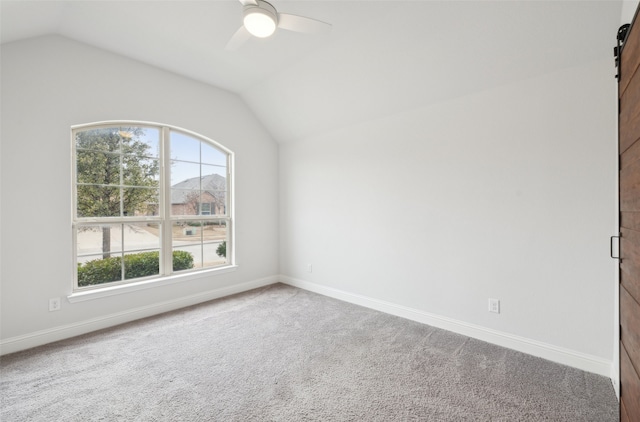 spare room featuring ceiling fan, lofted ceiling, a barn door, and carpet floors