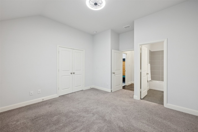 unfurnished bedroom with a closet, ensuite bath, vaulted ceiling, and carpet