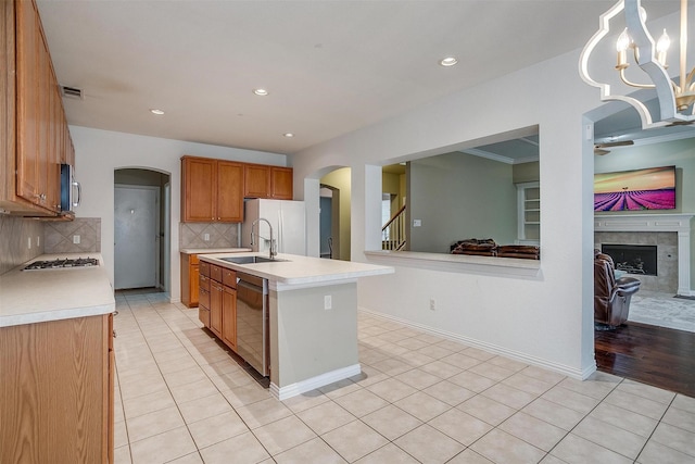 kitchen with light tile patterned flooring, pendant lighting, an island with sink, sink, and stainless steel appliances