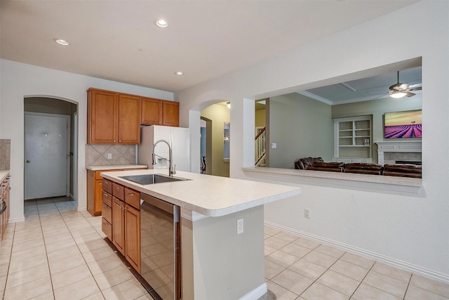 kitchen featuring sink, dishwasher, ceiling fan, tasteful backsplash, and an island with sink