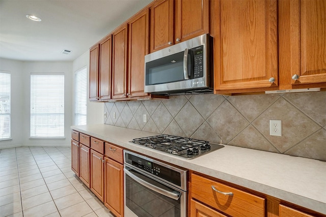 kitchen with stainless steel appliances, light tile patterned floors, and backsplash