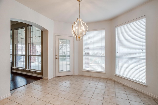 unfurnished dining area featuring light tile patterned flooring and a notable chandelier