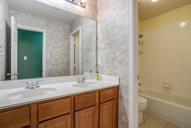 full bathroom with tile patterned flooring, vanity, tiled shower / bath, and toilet