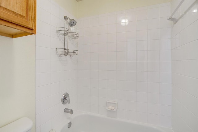 bathroom with tiled shower / bath combo and toilet