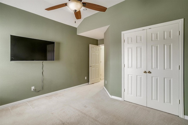 unfurnished bedroom featuring ceiling fan, a closet, vaulted ceiling, and light carpet