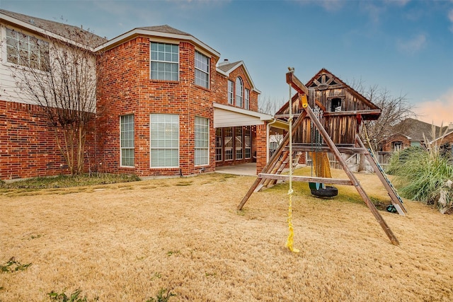 playground at dusk featuring a yard and a patio