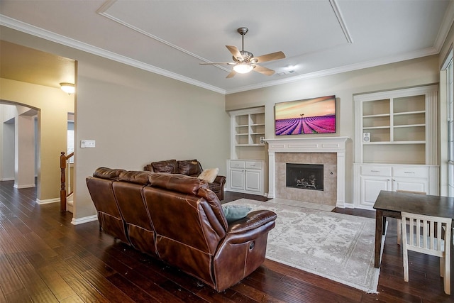 living room with ceiling fan, a fireplace, ornamental molding, and dark hardwood / wood-style flooring