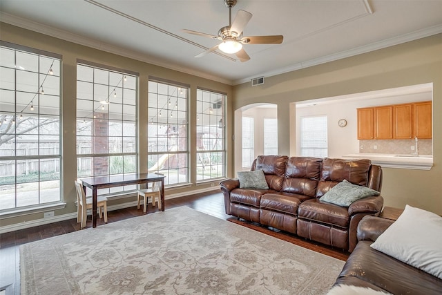 living room featuring dark wood-type flooring, ceiling fan, and ornamental molding