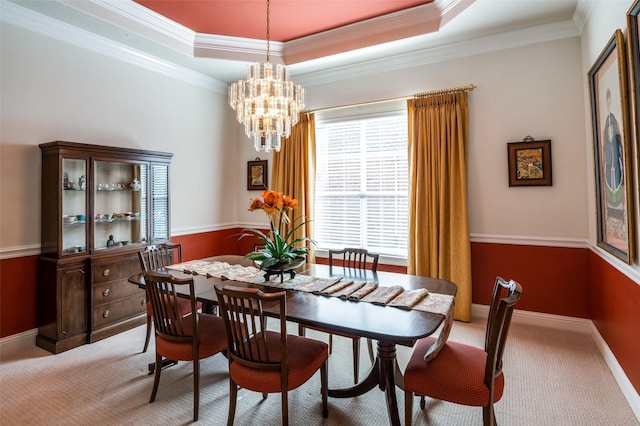 carpeted dining room featuring a chandelier, ornamental molding, and a raised ceiling